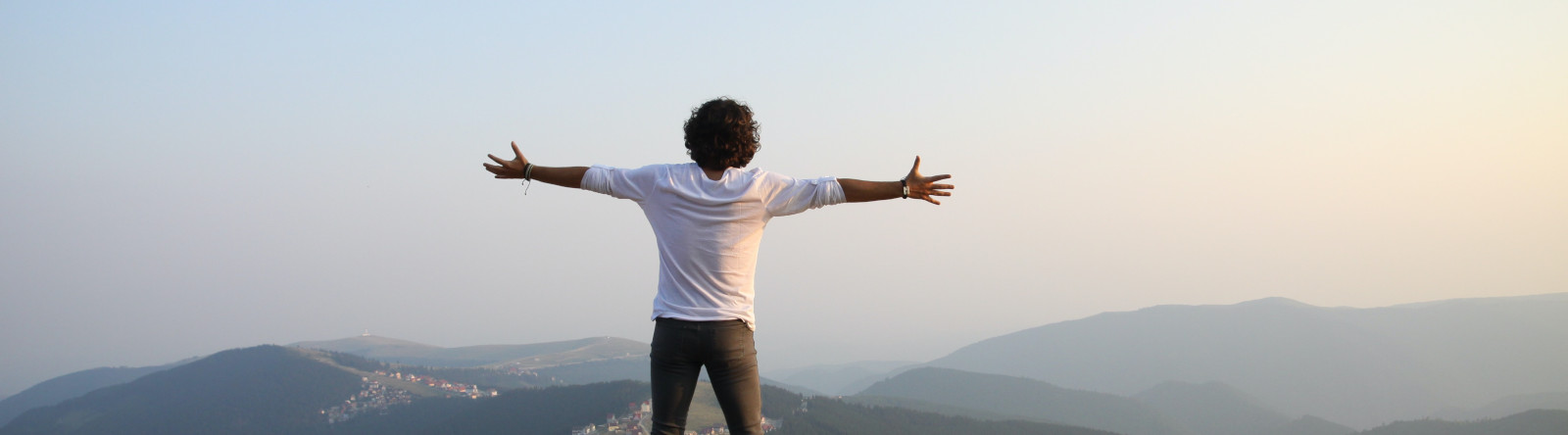 Man standing on mountain with outreached arms