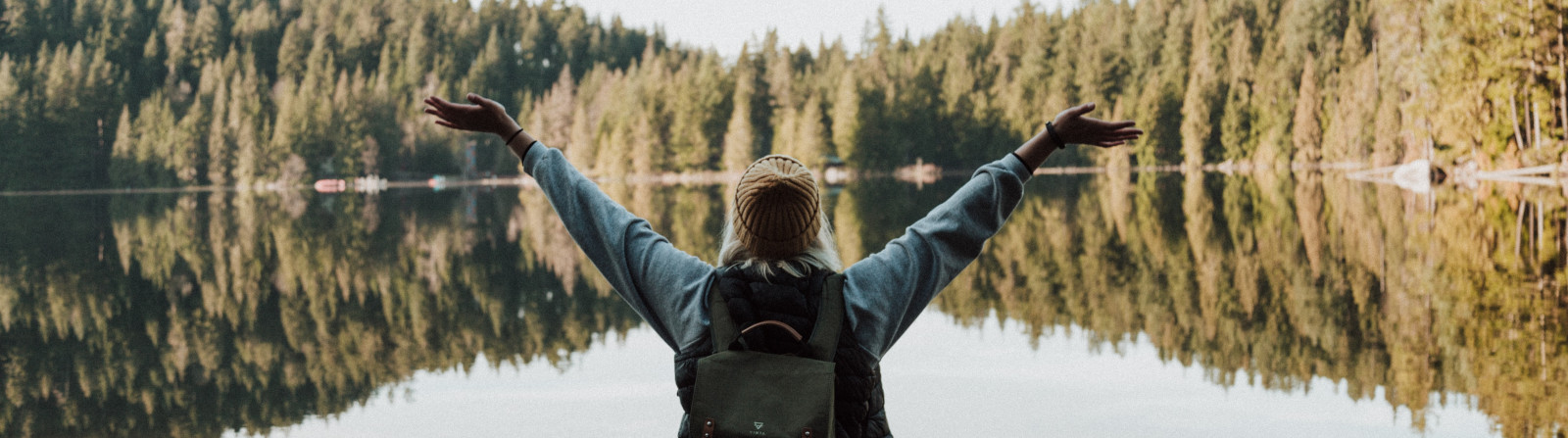 women overlooking lake with hands in air